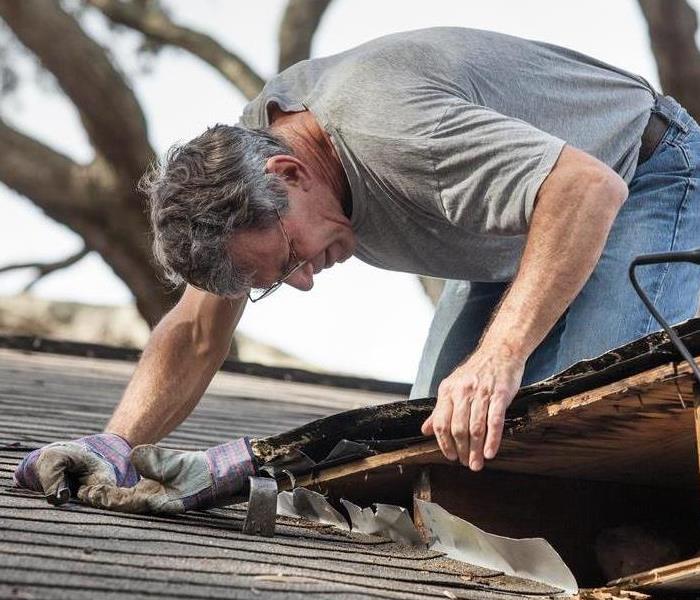 Man checking his roof damage after a storm. 